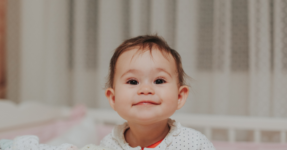 Bebê sorrindo e olhando para frente com olhar atento